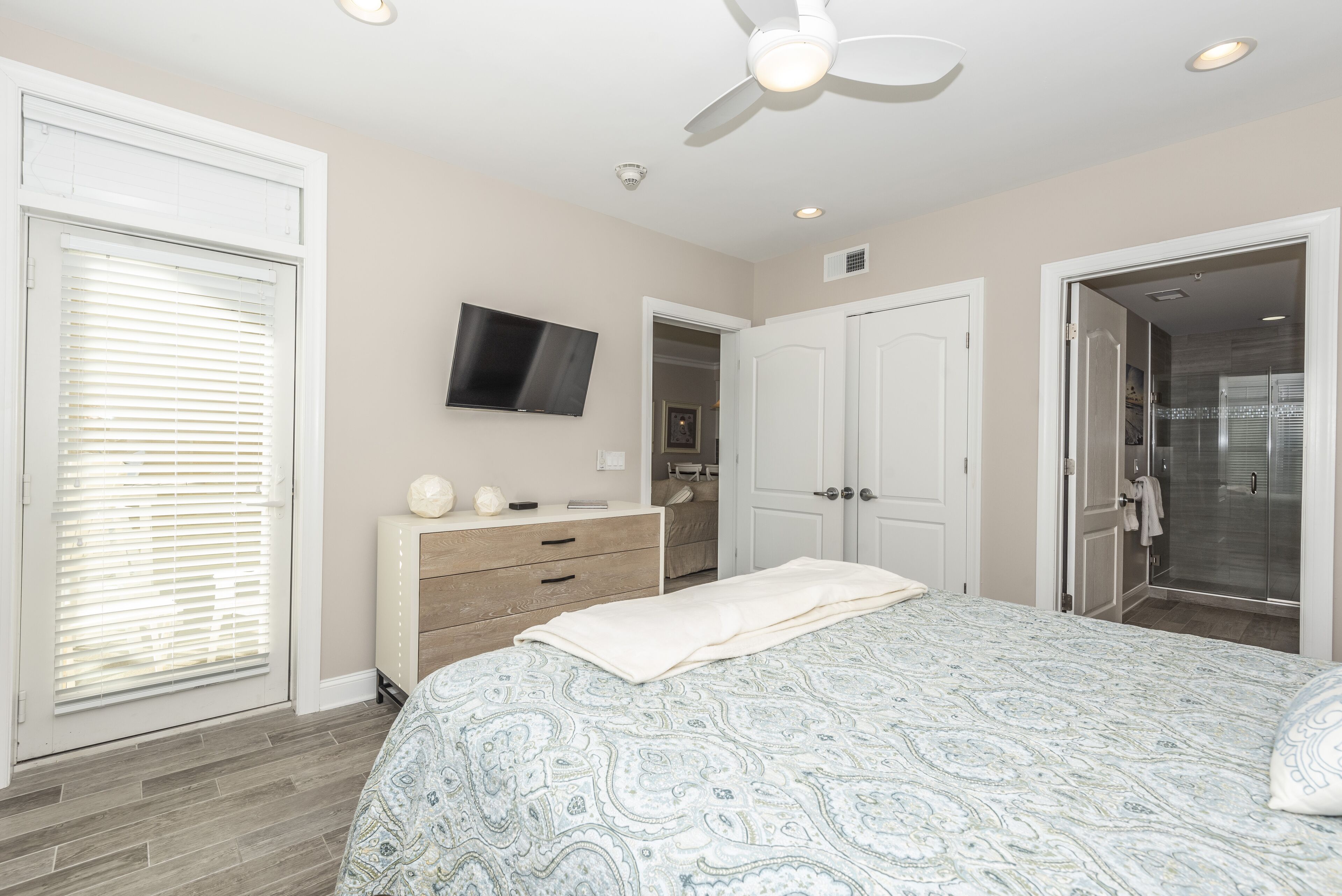 A bedroom with a bed, a dresser, a television, and a walk-in closet.