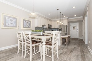 A modern kitchen with white cabinets, a central island, and pendant lighting.