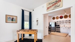 Ein Zimmer mit einem Kicker, einem Schild zum Kentucky Bourbon Trail, einem gerahmten Foto von Pferderennen und einer Küche mit Mikrowelle und Geschirrspüler.