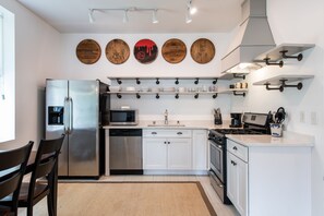 Une cuisine moderne avec des meubles blancs, des appareils en acier inoxydable et des éléments de décoration en bois fixés au mur.