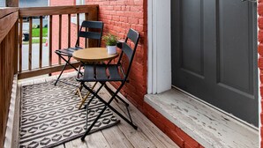Eine Holzterrasse mit Tisch und Stühlen, einer Tür und einer Backsteinmauer.