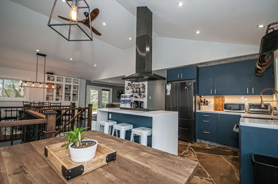 A modern kitchen with a central island, bar stools, and a built-in microwave.