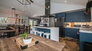 Une cuisine moderne dotée d’un îlot central, de tabourets de bar et d’un four à micro-ondes encastré.