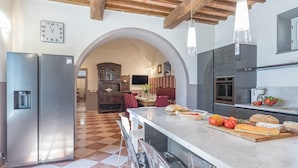 A kitchen with a marble countertop, stainless steel appliances, and a checkered floor. - Antica Villa Merelli 12, Emma Villas (Poggio Fabbrelli)