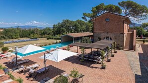A rooftop pool area with lounge chairs and umbrellas, a brick building, and a view of the surrounding landscape. - Antica Villa Merelli 12, Emma Villas (Poggio Fabbrelli)