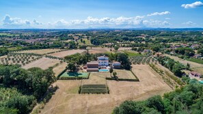 Vista aérea de una extensa propiedad con varias construcciones, jardines amplios y una piscina.