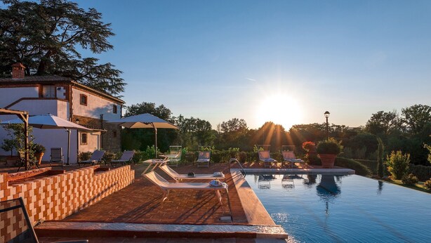 A poolside area with lounge chairs and umbrellas, a clear sky, and a sunset. - Antica Villa Merelli 12, Emma Villas (Poggio Fabbrelli)
