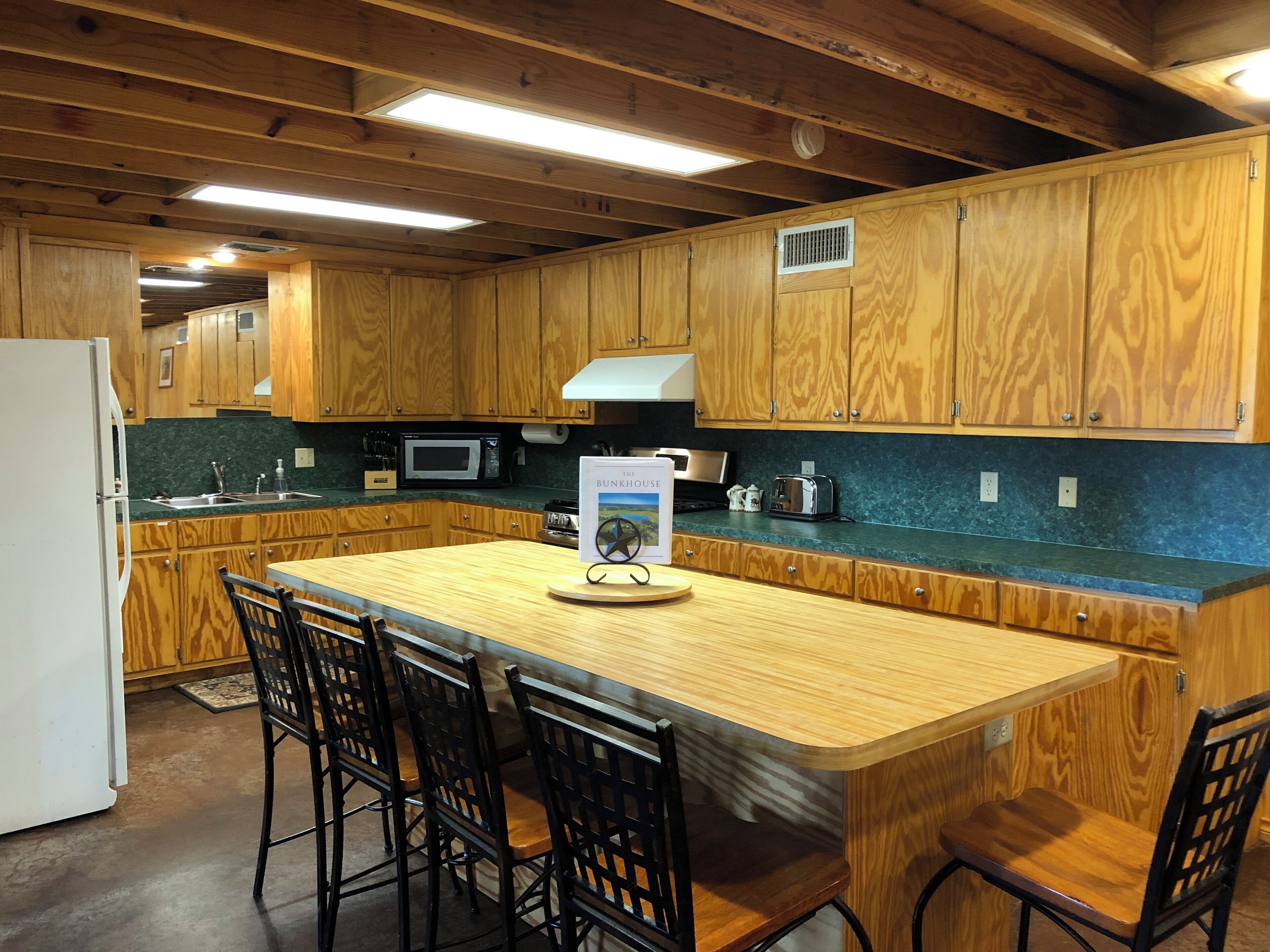 A kitchen with wooden cabinets, a microwave, a toaster, and a book on the counter.
