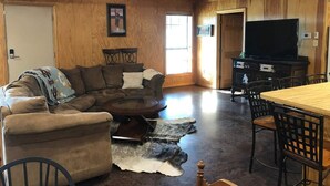 A cozy living room with a sectional sofa, a round coffee table, and a dining table with chairs.