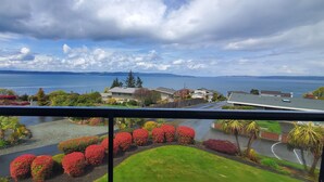 A residential area with a view of a large body of water, houses, and a well-maintained garden with red bushes. - Relaxing in an Entire 5,400sf Beach View Home With Indoor Heated Swimming Pool. (Federal Way)