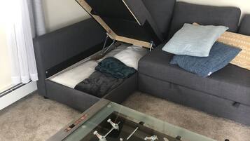 Un salon avec un canapé, une table de baby-foot et une fenêtre avec des rideaux.