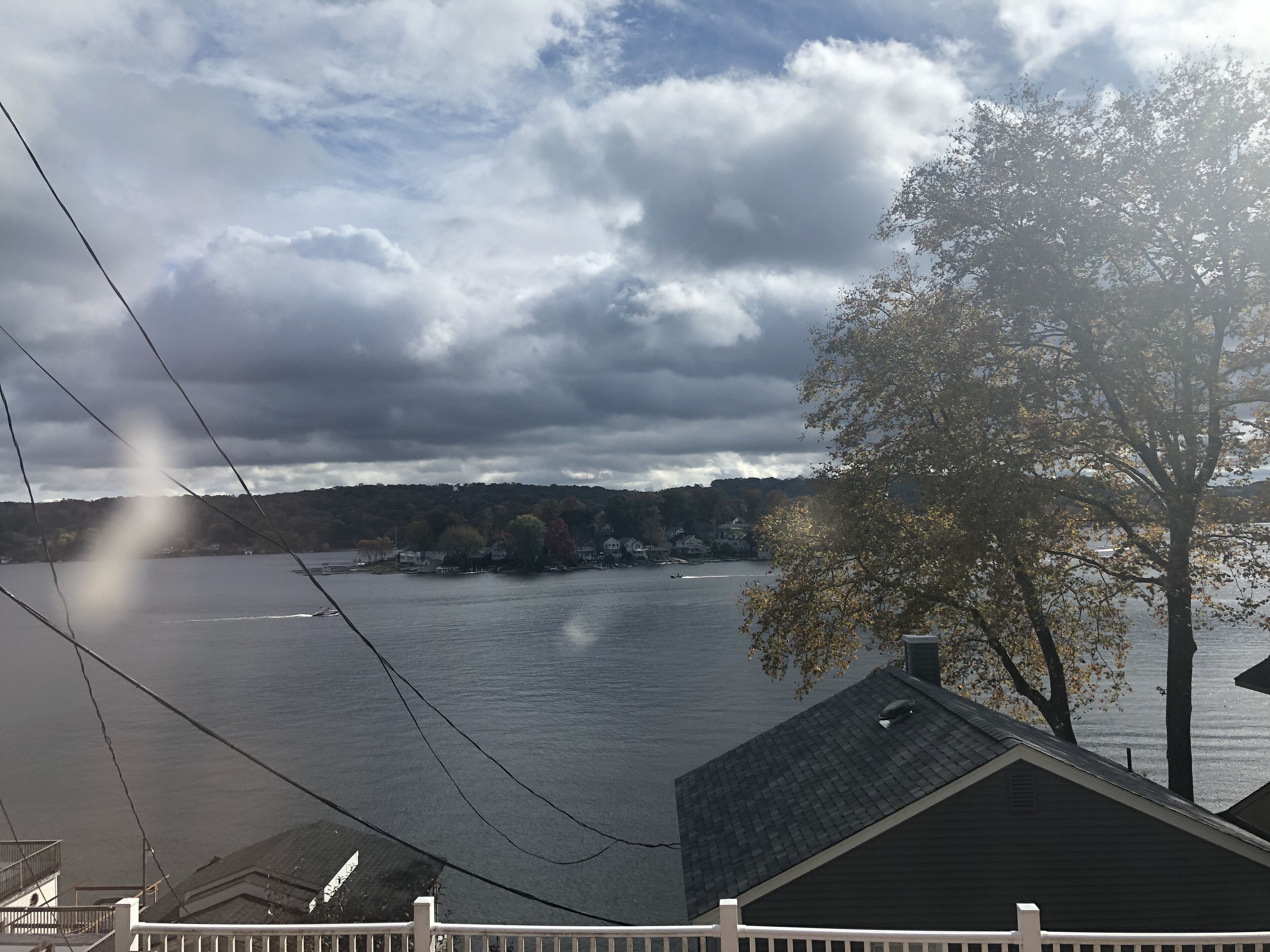 A view of a lake with a house in the foreground and a tree on the right.