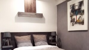 A bedroom with a bed, two bedside tables, a nightstand, a wall-mounted shelf, and a framed picture. - Wood Stone & Wine **** (Beaune)