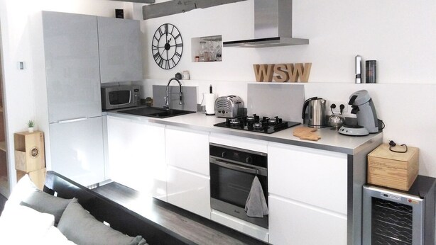A modern kitchen with white cabinetry, a stainless steel range hood, a microwave, a toaster, a kettle, and a coffee maker. - Wood Stone & Wine **** (Beaune)