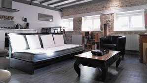 A modern living room with a sofa, a wooden coffee table, and a fireplace. - Wood Stone & Wine **** (Beaune)