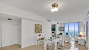 A modern, well-lit room with a dining area, a sofa, and a TV. - Beach Penthouse & Ocean Paradise (Hollywood)