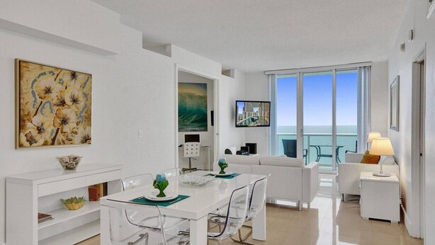 A modern hotel room with a dining area, a sofa, a TV, and a balcony with a view. - Beach Penthouse & Ocean Paradise (Hollywood)