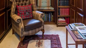 A library with bookshelves, a leather armchair, a rug, and a framed document on the wall. - Historic Fairytale Lickleyhead Castle (Insch)