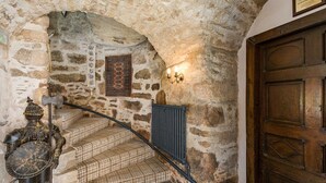 A stone-walled staircase with a metal railing, a wooden door, and a medieval suit of armor. - Historic Fairytale Lickleyhead Castle (Insch)