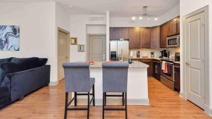 Una cocina moderna con armarios de madera, una isla central y una zona de comedor con un sofá y dos taburetes de bar.