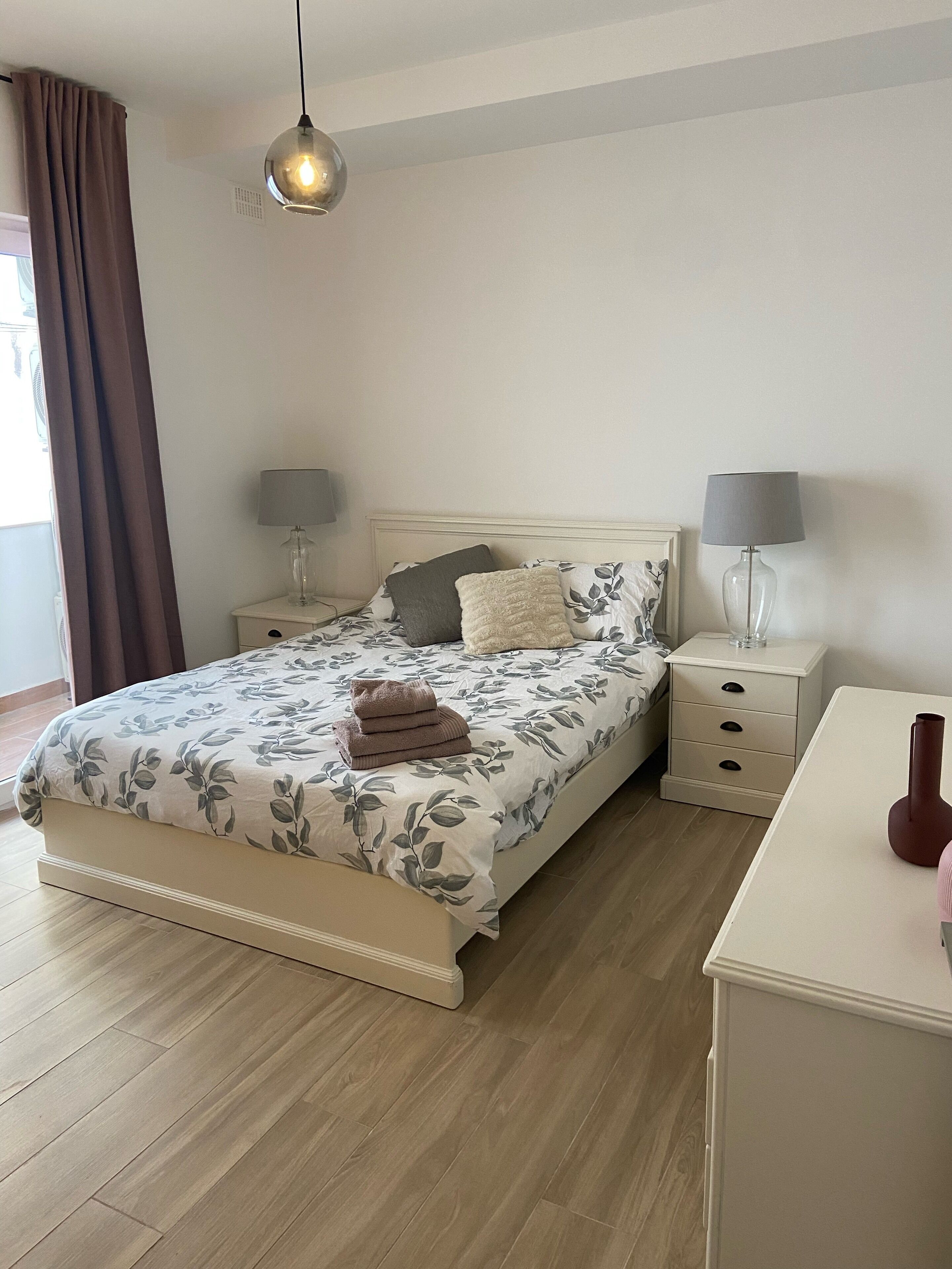 Une chambre à coucher avec un lit, des tables de chevet, une lampe et une commode.
