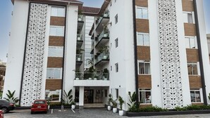 A multi-story hotel with a central entrance, balconies, and potted plants. - Zen Apartments (Lagos)