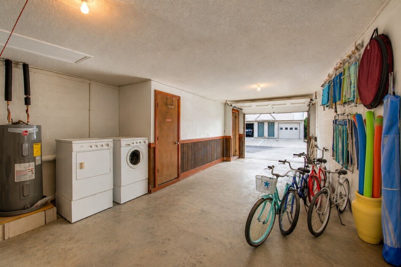 Una sala amb bugaderia, amb rentadores i assecadores, una porta de fusta i bicicletes aparcades al passadís.