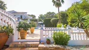 Un bâtiment blanc avec une clôture blanche, des marches en pierre et des plantes en pot.