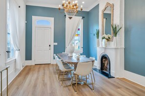 A dining area with a wooden table, white chairs, and a chandelier.