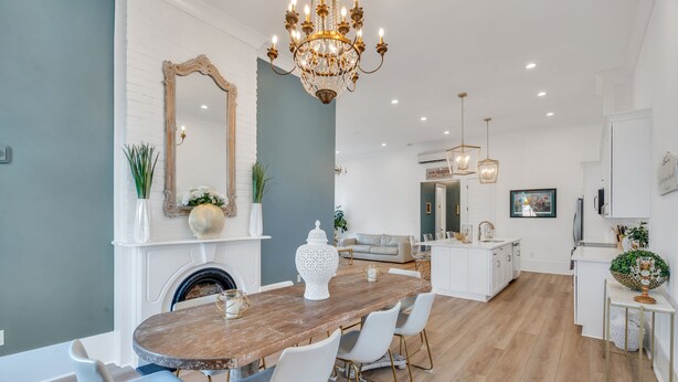 A modern kitchen with a wooden dining table, white chairs, and a chandelier. - Luxury 5BR Home, Walk to French Quarter!! (New Orleans)