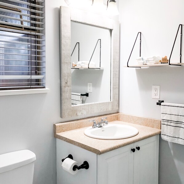 A bathroom with a white sink, a toilet, and a mirror with a wooden frame.