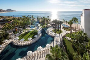 A resort with a pool, palm trees, and a view of the ocean. - Hilton Grand Vacations Club La Pacifica Los Cabos (San José del Cabo)