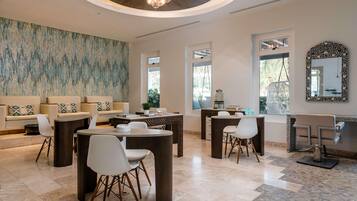 A modern interior with a sofa set, dining tables, chairs, a chandelier, and a large abstract wall painting.