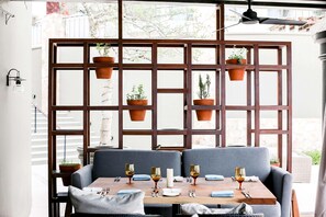 A dining area with a table set for four, a wooden partition with hanging planters, and a ceiling fan. - Hilton Grand Vacations Club La Pacifica Los Cabos (San José del Cabo)