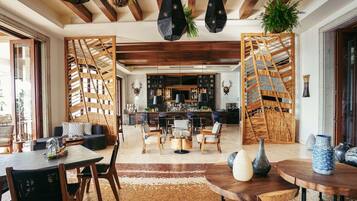 A spacious living area with a wooden ceiling, a bar area, and a seating arrangement.