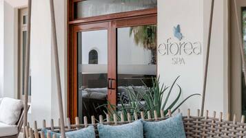 A spa entrance with a wooden door, a sign reading 'eforea SPA,' and a wicker bench with cushions.