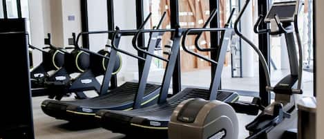 Un gimnasio con cintas de correr, bicicletas estáticas y una máquina de remo.
