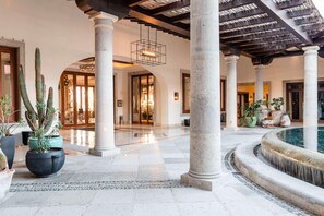 A spacious lobby with a pool, columns, and potted plants. - Hilton Grand Vacations Club La Pacifica Los Cabos (San José del Cabo)