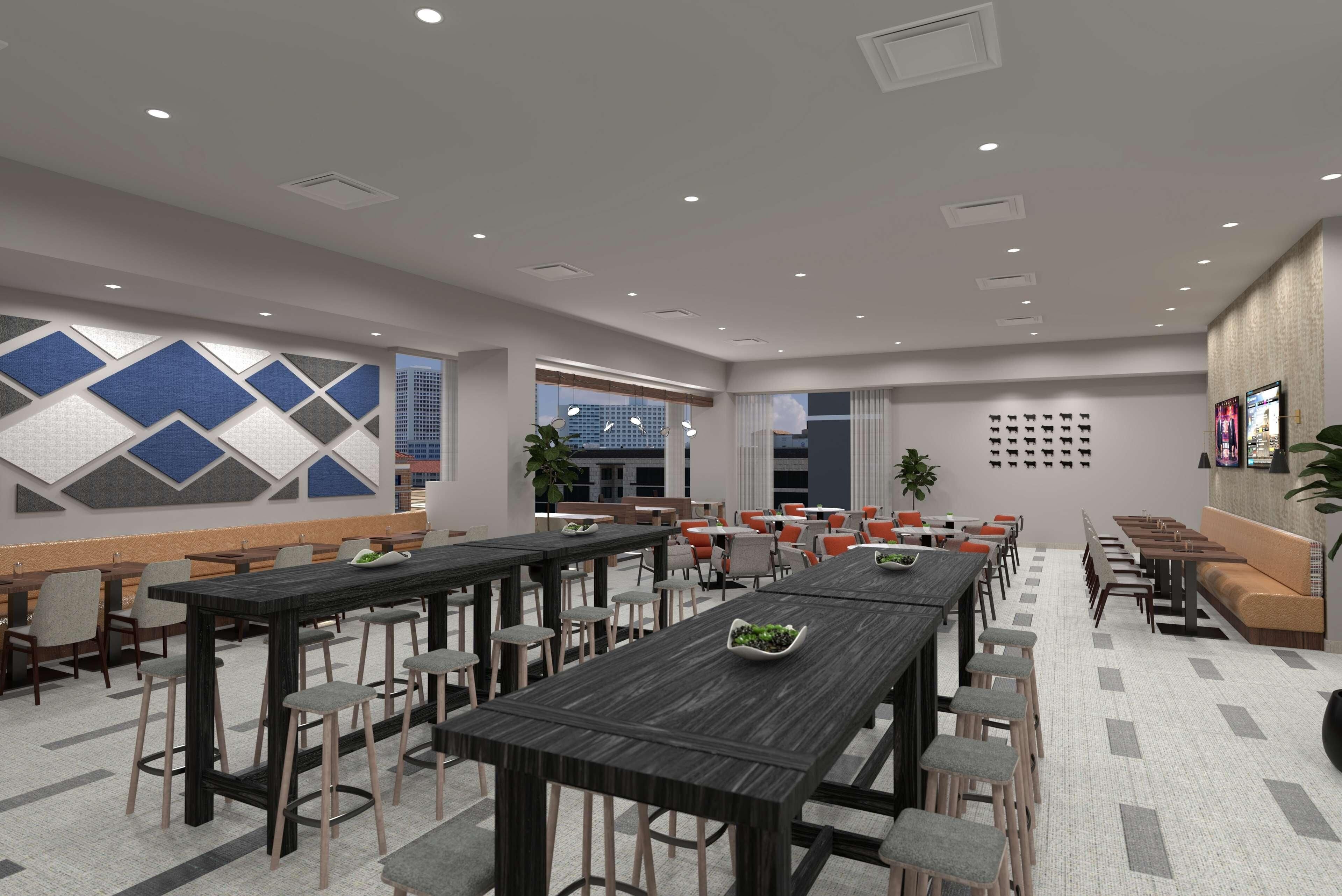 A spacious dining area with multiple tables and chairs, a patterned wall, and a large window providing a view of the city.