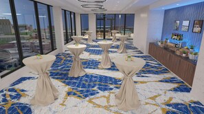 A hotel lobby with round tables, a bar area, and large windows offering city views. - Hilton Grand Vacations Club La Pacifica Los Cabos (San José del Cabo)