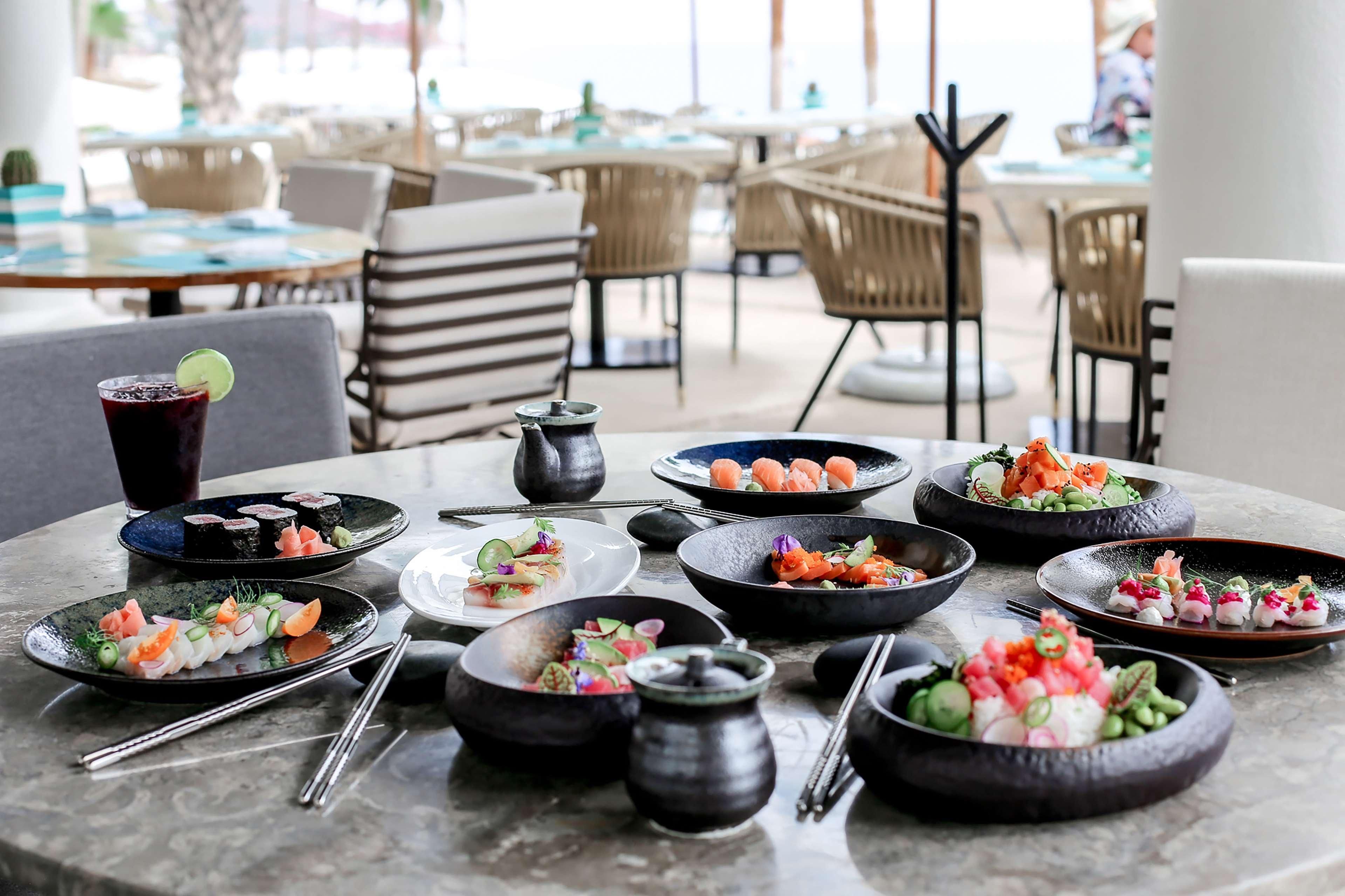 A dining table with various dishes, including sushi and a drink, in a restaurant setting.
