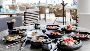 A dining table with various dishes, including sushi and a drink, in a restaurant setting.