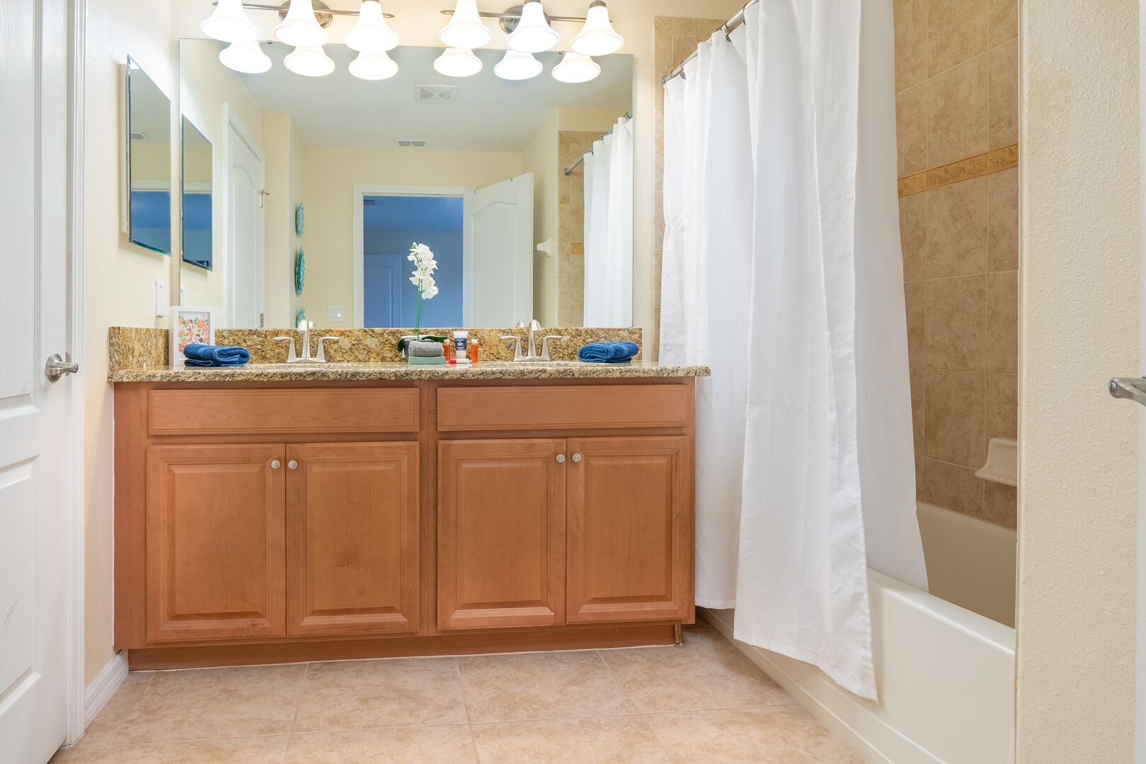 A bathroom with a double vanity, a large mirror, and a shower curtain.