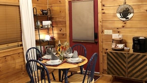 Una cabaña acogedora de madera con comedor, que incluye una mesa redonda, sillas y un rincón para café.