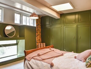 A bedroom with a bed, a window, a mirror, and green cabinets. - A fantastic and truly unique holiday suite located within the main castle. (Delgaty, near Turriff)