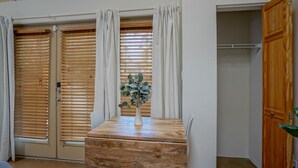 Une pièce avec une table en bois, un vase avec une plante et une armoire avec des stores en bois.