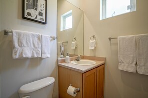 A bathroom with a toilet, sink, and two towel racks with white towels. - Downtown Modern Studio, centrally located (Albuquerque)