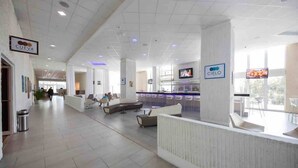 En rummelig lobby med reception, siddeområde og et fjernsyn.