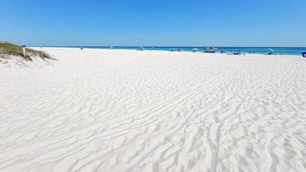 En bred sandstrand med en klarblå himmel.