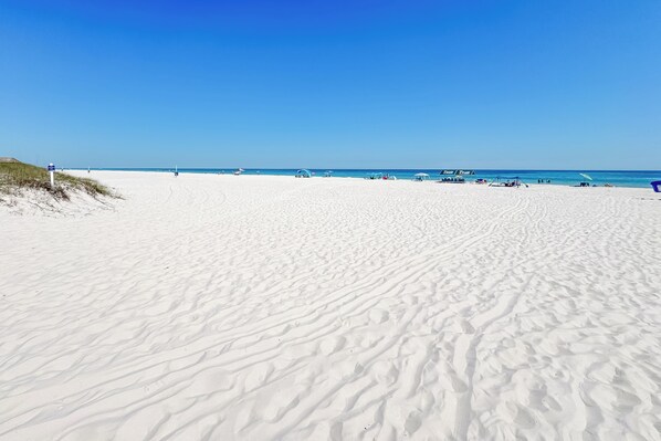 A wide sandy beach with a clear blue sky.